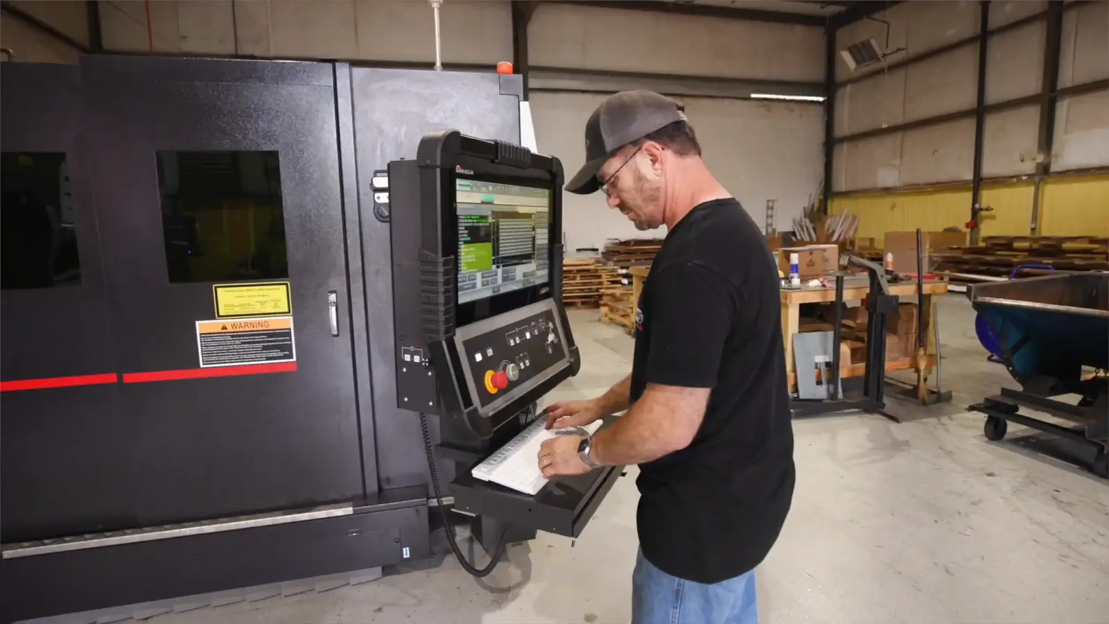 Evans operator running a job at the AMADA fiber laser cutting cell