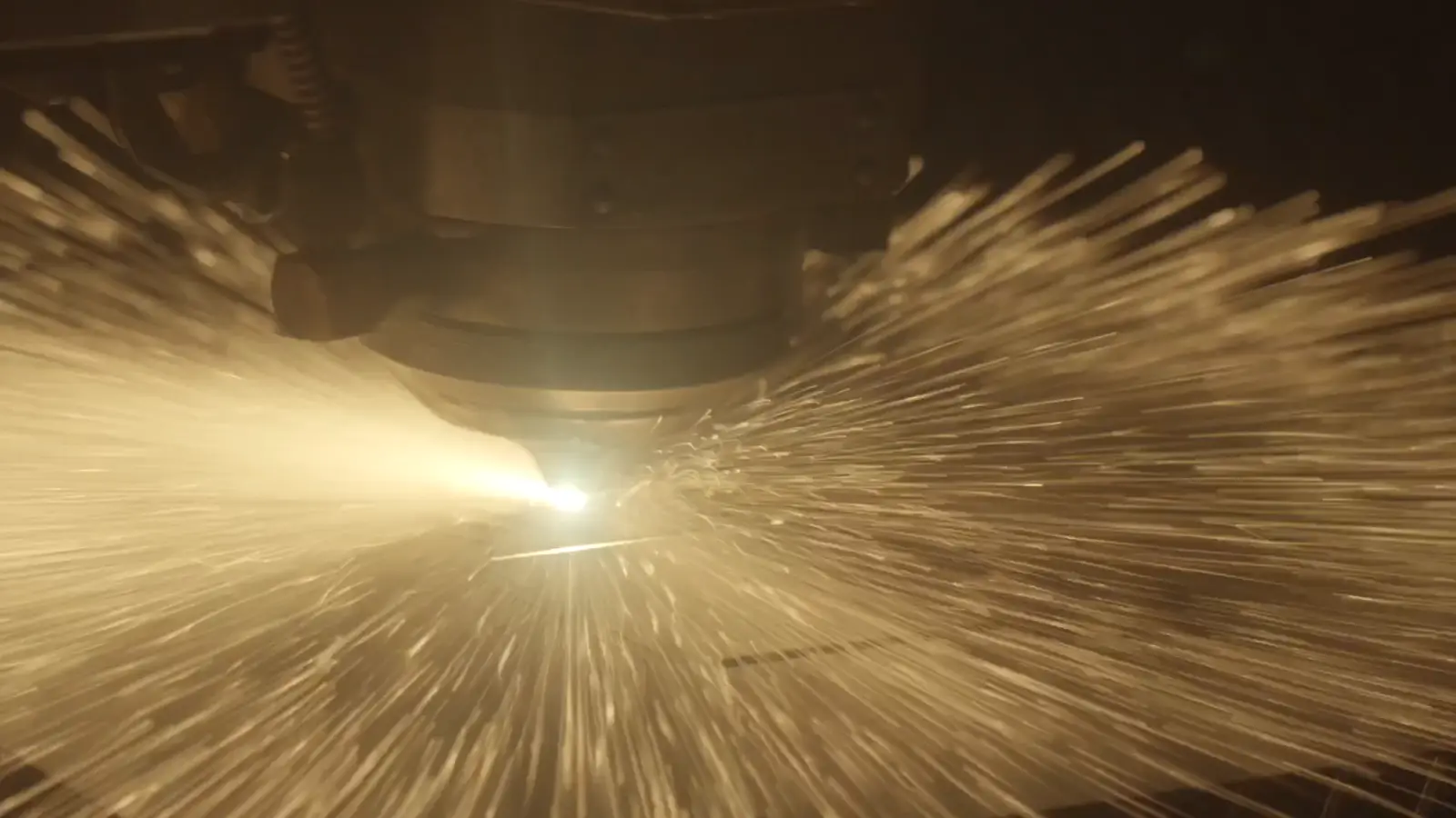 Sparks bursting from the fiber laser as it pierces steel plate