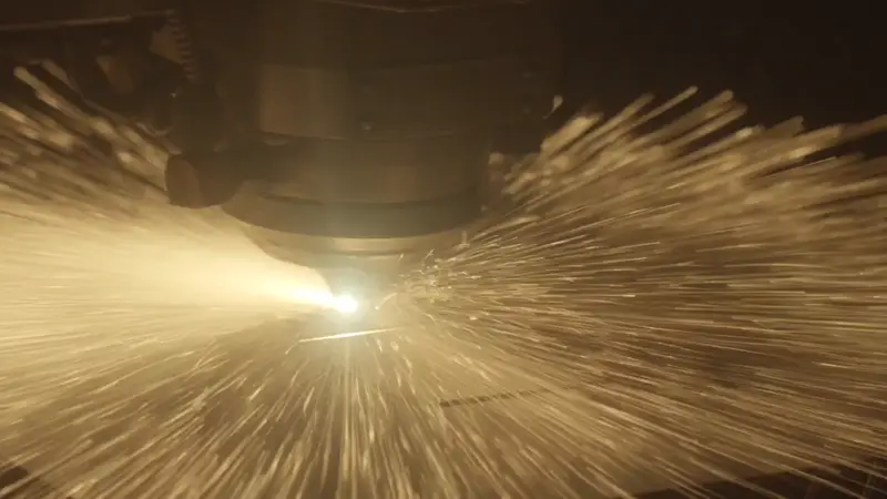 Sparks bursting from the fiber laser as it pierces steel plate