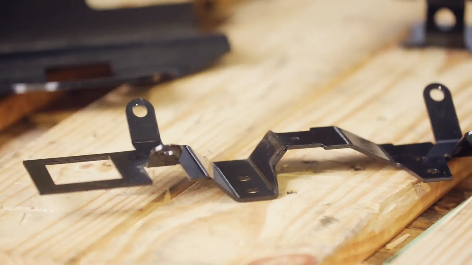 Freshly laser-cut steel brackets resting on the workbench