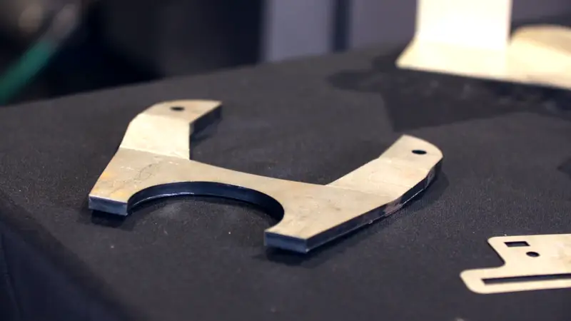 A precision laser-cut steel component on a dark backdrop