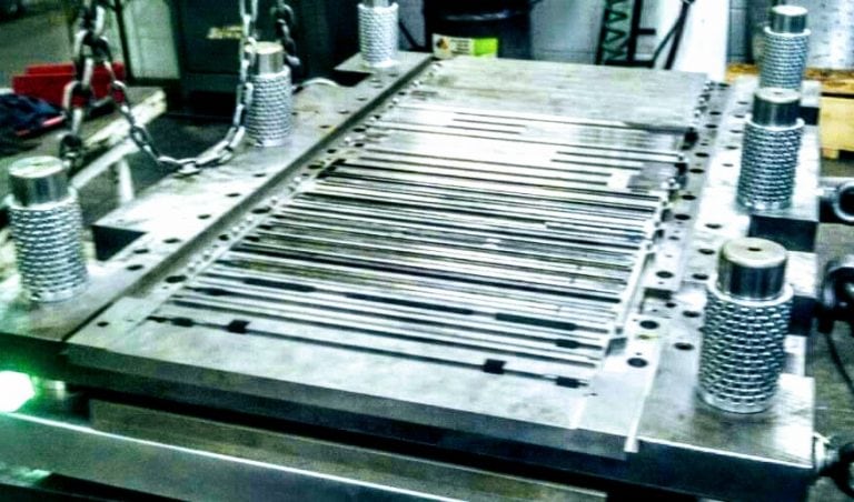 Progressive metal stamping die (bottom) for a surgical instrument